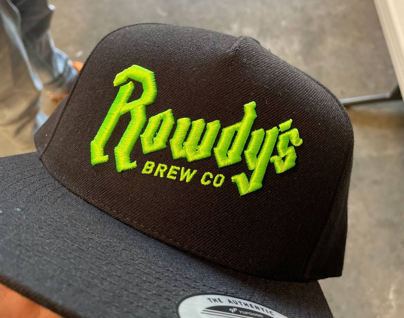 Black trucker hat with green embroidered Rowdy's Brew Co logo