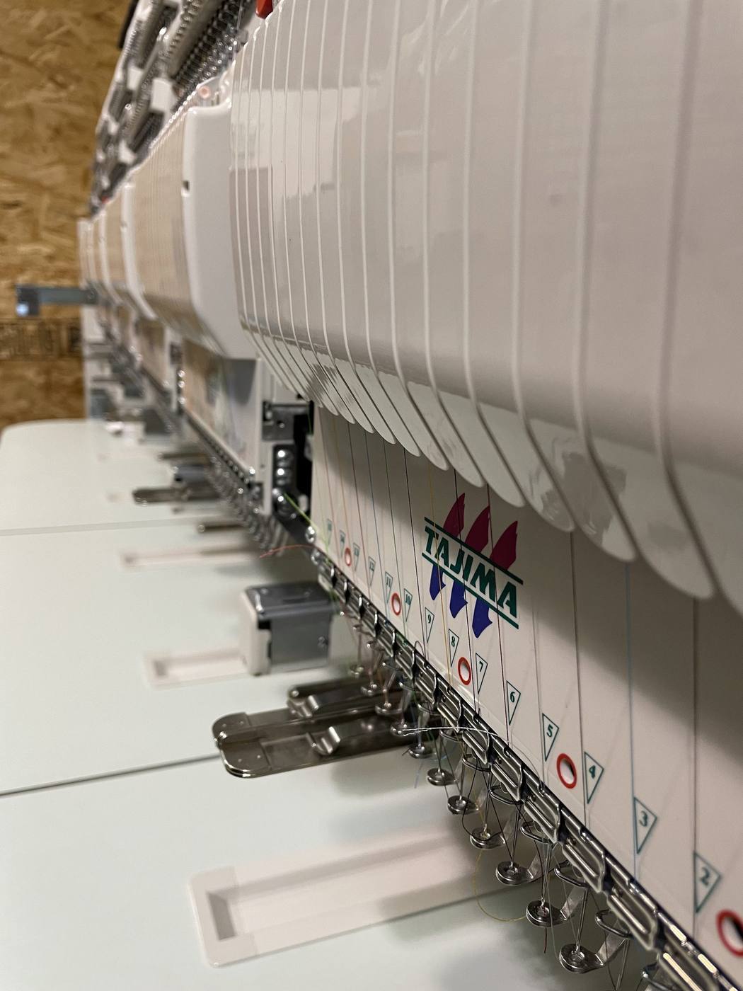 Multi-head commercial embroidery machine running a production order